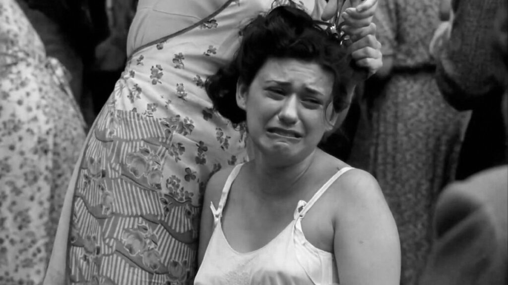 Band of Brothers liberation scene where a crying woman is forced to have her hair cut by townspeople in a public punishment moment