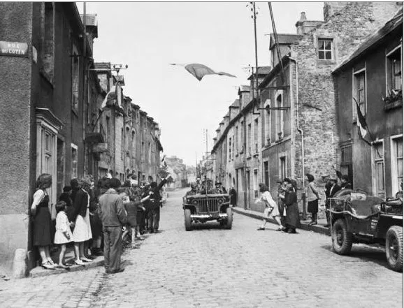 U.S. VII Corps jeep passing under French flag during the liberation of Carentan, 1944